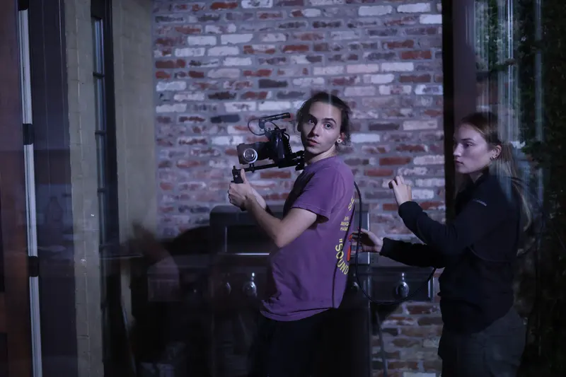 Camera operator with a gimbal rig in a dim brick room