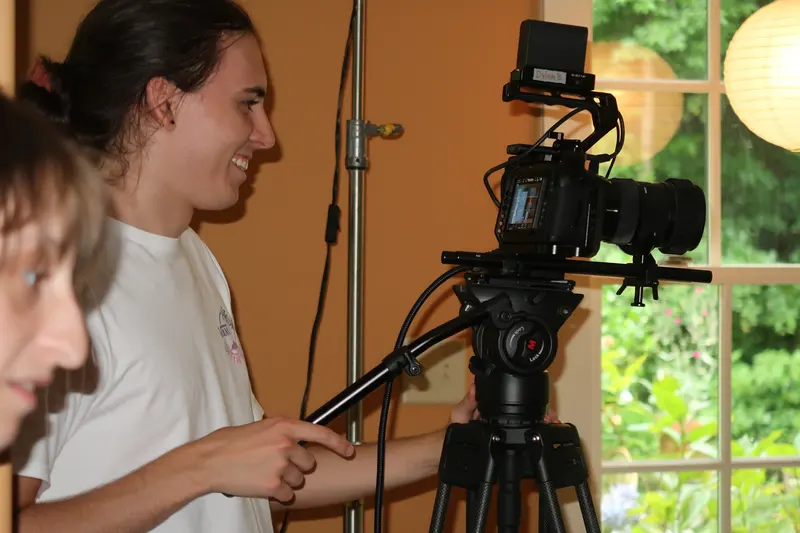 Crew member operating a cinema camera on a tripod