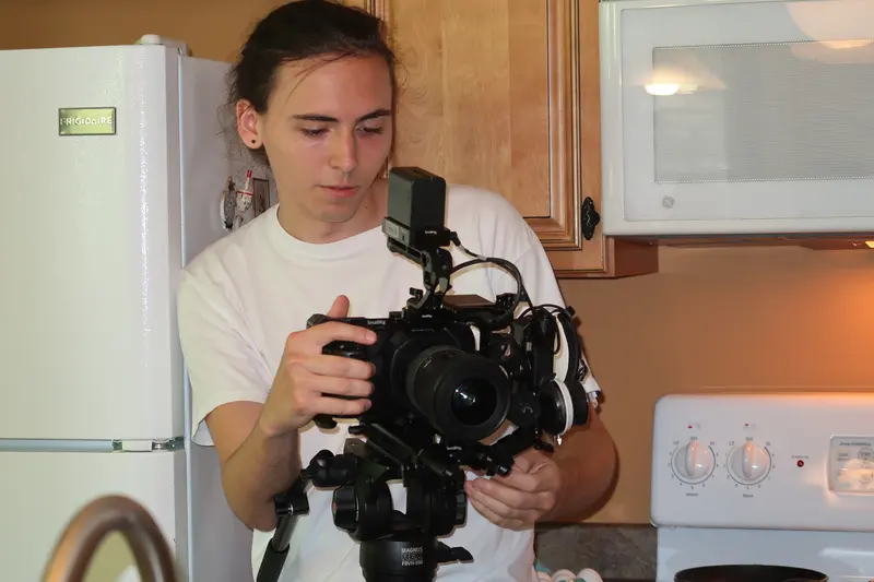 Camera operator holding a rigged cinema camera in a kitchen