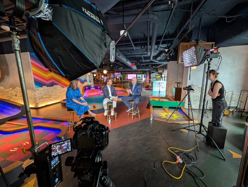 Studio interview set with colorful lighting and crew adjusting a light